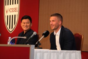 Rakuten CEO Hiroshi “Mickey” Mikitani and Lukas Podolski talk to journalists.
