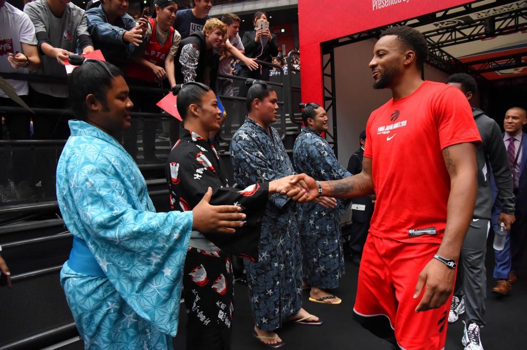 Raptors guard Norman Powell greets sumo wrestlers on his way out of the lockers.